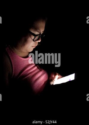 Lady using her smartphone in the dark. Stock Photo