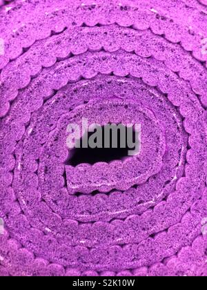 Closeup of a rolled up thick purple yoga mat. Stock Photo