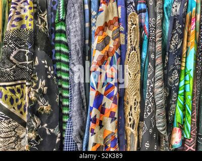 Side view of many fashionable colorful patterned clothes hanging on a clothing rack. Stock Photo