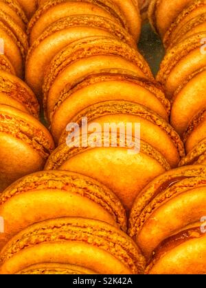 Fresh baked tasty treats orange macaron cookies and matching filling as a mouth watering delicious dessert. Stock Photo