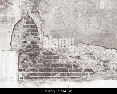 Black and white old wall with crumbling plaster and exposed bricks Stock Photo