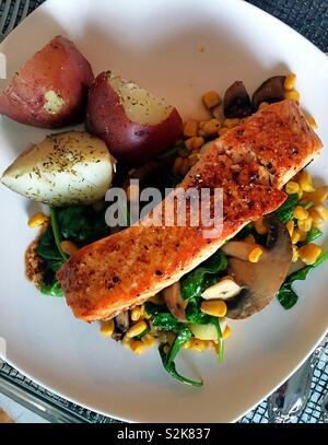 Gourmet meal of seared salmon fillet on a bed of fresh spring vegetables, USA Stock Photo