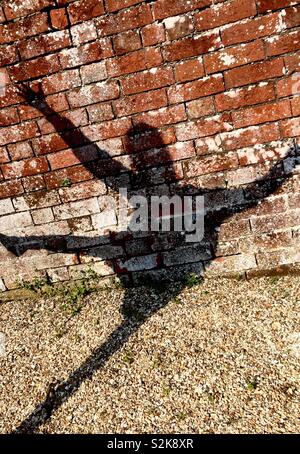 Female child shadow on the wall and gravel path jumping Stock Photo
