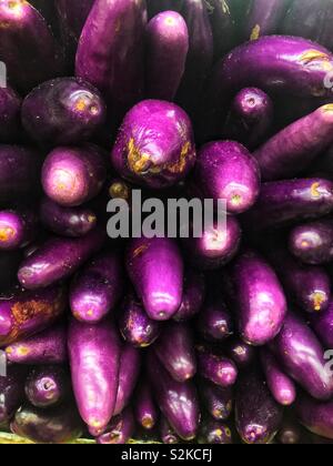 Full frame of farm fresh purple Chinese Eggplant stacked and piled on display and for sale at the local produce vendor. Stock Photo