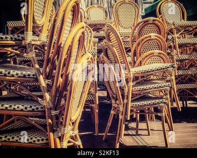 Stacks of wood and wicker chairs awaiting the opening of an outdoor café in Bryant Park, NYC, USA Stock Photo