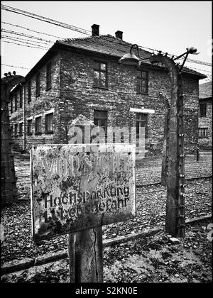 A electric fence warning sign at the infamous Auschwitz Nazi Concentration Camp. This site was witness to mass extermination mostly of Jewish People from 1942 to 1944. Now a Memorial Museum. Stock Photo