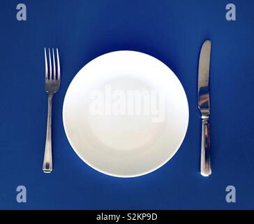 Plate knife and fork on blue background Stock Photo
