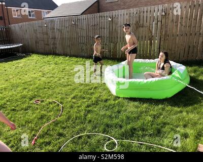 3 kids playing in a paddling pool Stock Photo