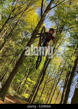 Mountain biker getting big air over a jump in the forest Stock Photo
