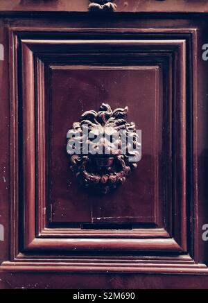 Door knocker in the shape of lion head on the red door in Paris Stock Photo