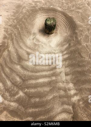 Patterns in the sand around an old wooden stump. Stock Photo