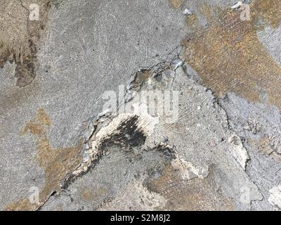 Detail of distressed concrete surface with cracks and remains of previous coverings, creating abstract grunge background Stock Photo