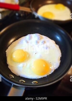 Two eggs frying in its stove top skillet, USA Stock Photo