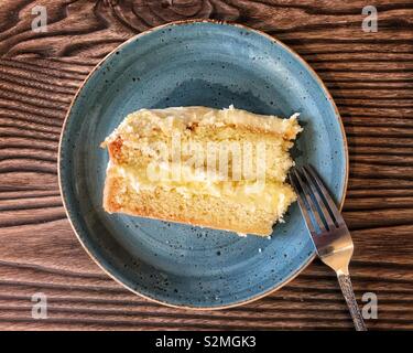 Top down shot of a slice of lemon sponge cake on a blue plate. Stock Photo