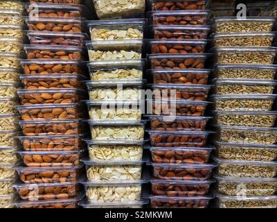 Stacked plastic containers full of raw almonds, roasted almonds, sliced almonds, and sunflower seeds on display and for sale at the local produce market. Stock Photo