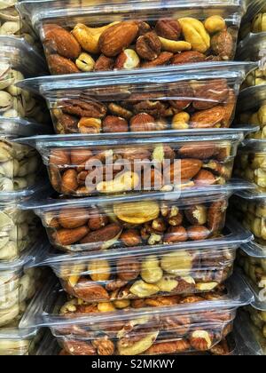 Stacked plastic containers full of mixed nuts on display and for sale at the local produce market. Stock Photo