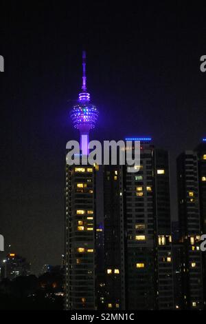 TV Tower, communications tower. Kuala Lumpur, Malaysia. By night, illuminated. Surrounded by apartment buildings. Stock Photo