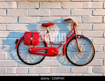 Red bike on a white brick wall- Decorative wall model bike. Stock Photo