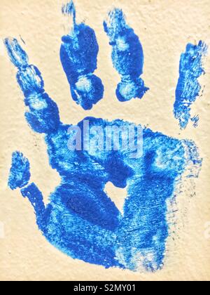 Child’s handprint in blue paint using hand painting techniques. Stock Photo