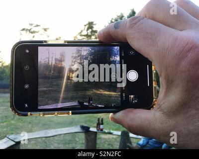 Hand Holding an iPhone While taking a photo Stock Photo