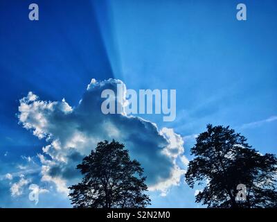 Crepuscular Rays Of sunlight shoot out from behind a silver lined cloud. These light rays are also called Splintered Rays, God’s Fingers, Sunbeams, Shafts from Heaven & Sun Rays. Photo © COLIN HOSKINS Stock Photo