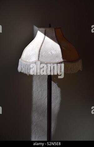 A Victorian floor lamp stands in both shadow and light. Stock Photo