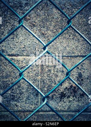 Mesh wire fence with wall behind. Stock Photo