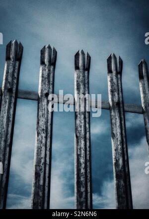 Metal security fence with spiked tops against sky. Stock Photo