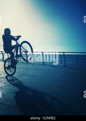 Teenage boy playing on the bike on the beach Stock Photo