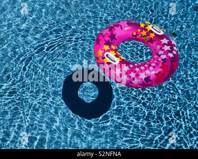 Pink ring floating in pool with shadow below Stock Photo
