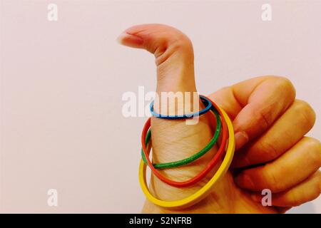 One thumb up for colourful rubber bands on a hypermobile thumb. Stock Photo