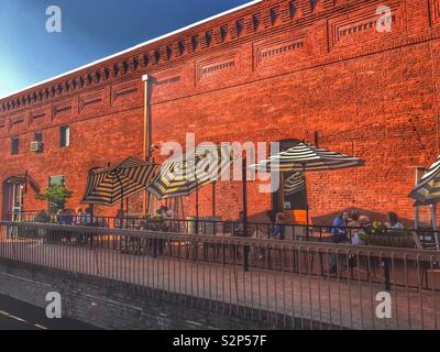 People out having dinner on the patio along side an old brick building wall. Stock Photo