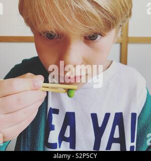 Boy using chopsticks Stock Photo