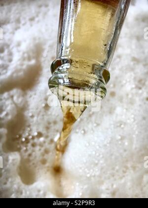 Lager beer being poured from a bottle resulting in a large amount of froth Stock Photo