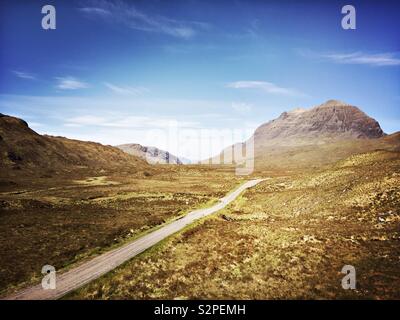 A single-track road runs through a valley in the Highlands of Scotland. Stock Photo