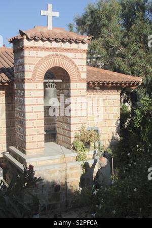 Greek Orthodox priest watering flowers at the church of St George Makrygiannis, adjacent to the Acropolis Museum in Athens, Greece. Stock Photo