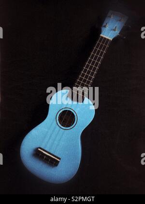 Blue ukulele on a black background. Stock Photo
