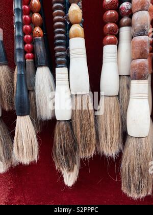 Large calligraphy brushes hang on red velvet in Chinatown Singapore Stock Photo
