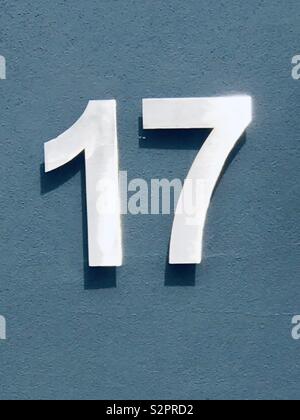 Number seventeen made of white painted metal on a  blue door Stock Photo