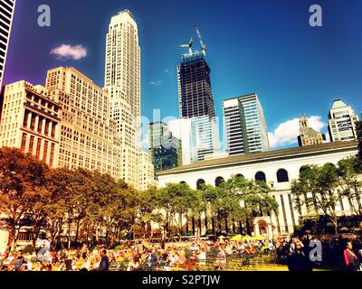 Many people enjoy outdoor lawn in Bryant Park behind the new York public library, NYC, USA Stock Photo