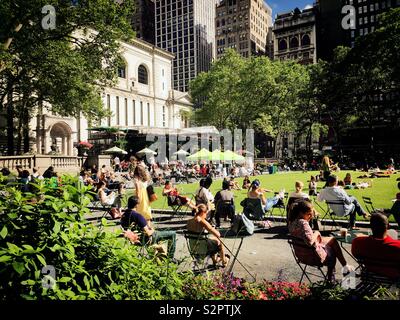 Many people enjoy the outdoor lawn and Terrace in Bryant Park behind the new York public library, New York City, USA Stock Photo