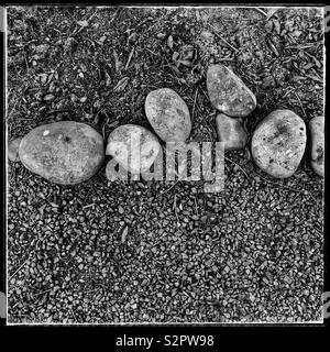 Small smooth stones on ground. Black and white photo. Stock Photo