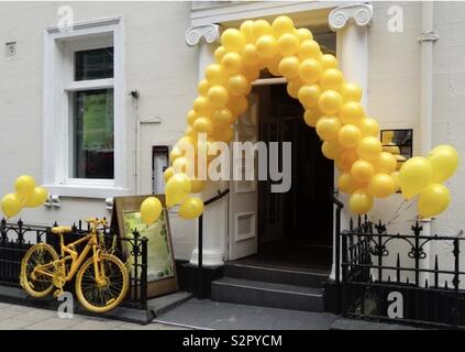 Office doorway in central Leeds, Yorkshire, UK, decorated with many yellow balloons and accompanied by a yellow cycle for the 101st Tour de France due to start on the 5th July, 2014. Stock Photo