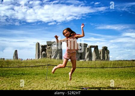 Girl jumping in front of Stonehenge Stock Photo