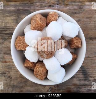 Looking down from above onto a bowl full of brown and white sugar cubes in a square Instagram style frame Stock Photo