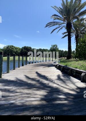 Bridge walkway with large shadows on the path from palm trees Stock Photo