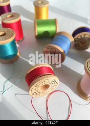 Detail of vintage wooden spoons of multi colored thread on a white background Stock Photo