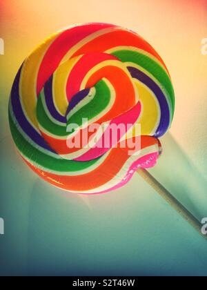 Vibrant swirling multi colored candy lollipop on a stick close up Stock Photo