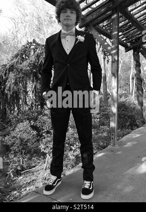 Prom. Boy in tuxedo standing in archway with hands in pocket wearing vans tennis  shoes. Nature. Flowers bushes in background. Black and white picture Stock  Photo - Alamy