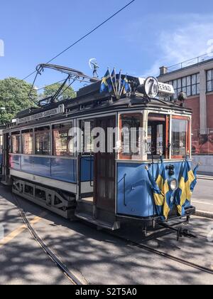An old blue tram with Swedish national flags in Stockholm, Sweden Stock Photo